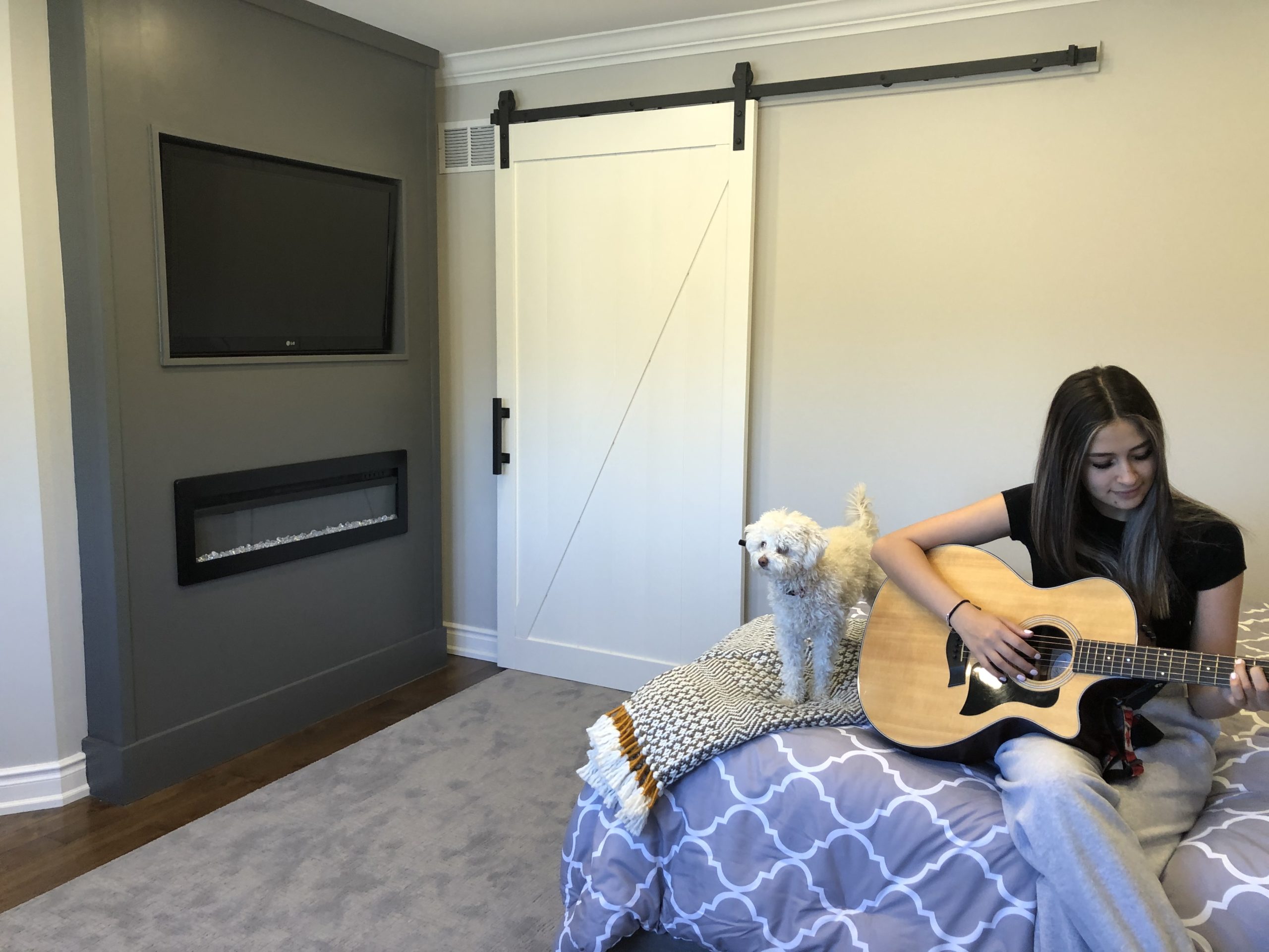 IMG_9808 White Barn Door behind teen girl sitting with a small white dog playing guitar on her bed.